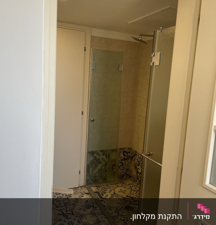 מקלחת עם דלת זכוכית ורצפה מעוטרת